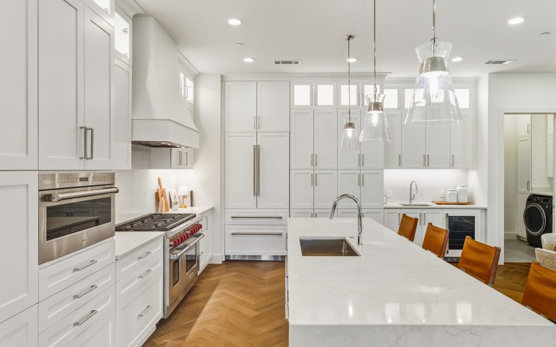 a kitchen with white cabinets and pendant lighting